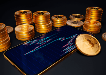 Celular con gráfico de trading junto a bitcoins.