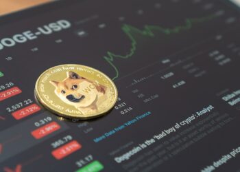 moneda de Dogecoin sobre pantalla mostrando grafico de precio en alza dentro de plataforma de trading