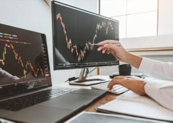 trader señala gráfico de precio en pantallas de computadora