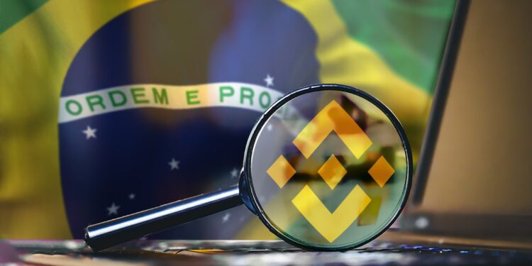 Lupa con logo de Binance sobre computadora con bandera de Brasil en el fondo