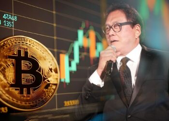 moneda de bitcoin apoyada en pantallacon gráfico de precio en aumento junto a imagen de Robert Kiyosaki