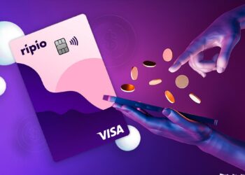 tarjeta visa de Ripio junto a manos con monedas digitales sobre teléfono móvil