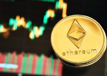 Moneda de Ethereum sobre superficie de vidrio con grafico de trading en el fondo