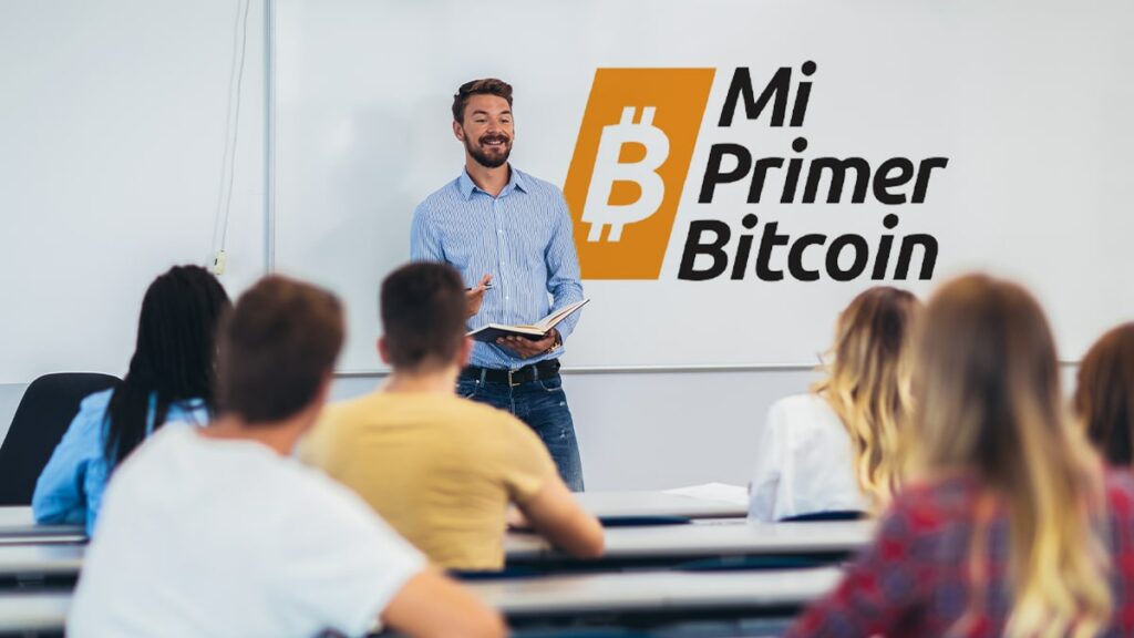 profesor dando clase a jovenes adultos con logo de Mi Primer Bitcoin en la pizarra