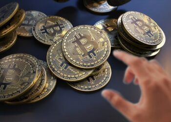 mano acercandose a agarrar monedas de bitcoin en mesa