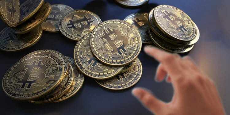 mano acercandose a agarrar monedas de bitcoin en mesa
