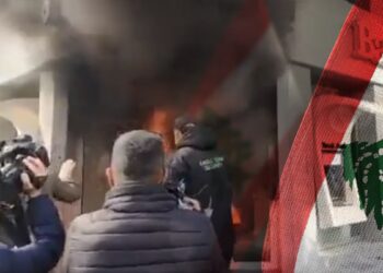 protestantes incendiando sede bancaris junto a bandera de Libano