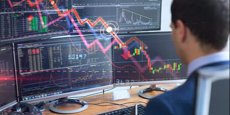 trader analizando gráficos de mercado en multiples pantallas de computaodra con grafico descendente superpuesto