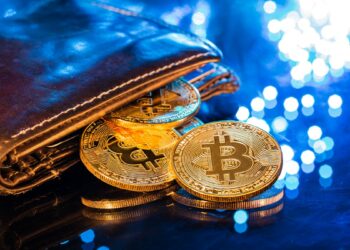 Moneas de bitcoin saliendo de billetera sobre mesa de cristal con luces reflejadas