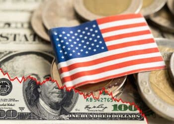 grafico bajista conformado por billete de dolar rasgado con monedas y billetes de dólares con bandera de los Estados Unidos