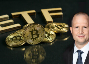 Nate Geraci junto a monedas de bitcoin apiladas sobre mesa con ETF en el fondo