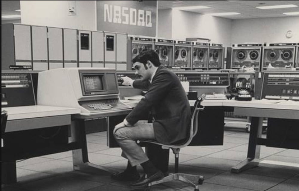 Sala computadoras para almacenamiento de datos muy antigua, años 1970, con una persona viendo la pantalla de una terminal.