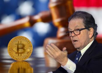 Art Laffer junto a moneda de bitcoin sobre escritorio con martillo de juez y bandera de estados unidos en el fondo