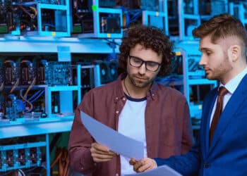 Hombres preocupados observando documentos con mineros de criptomonedas en el fondo