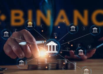 personas apilando monedas con bancos digitales conectados en red y logo de binance en el fondo