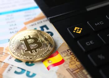 moneda de bitcoin sobre billetes de euros junto a calculadora con logo de bitcoin