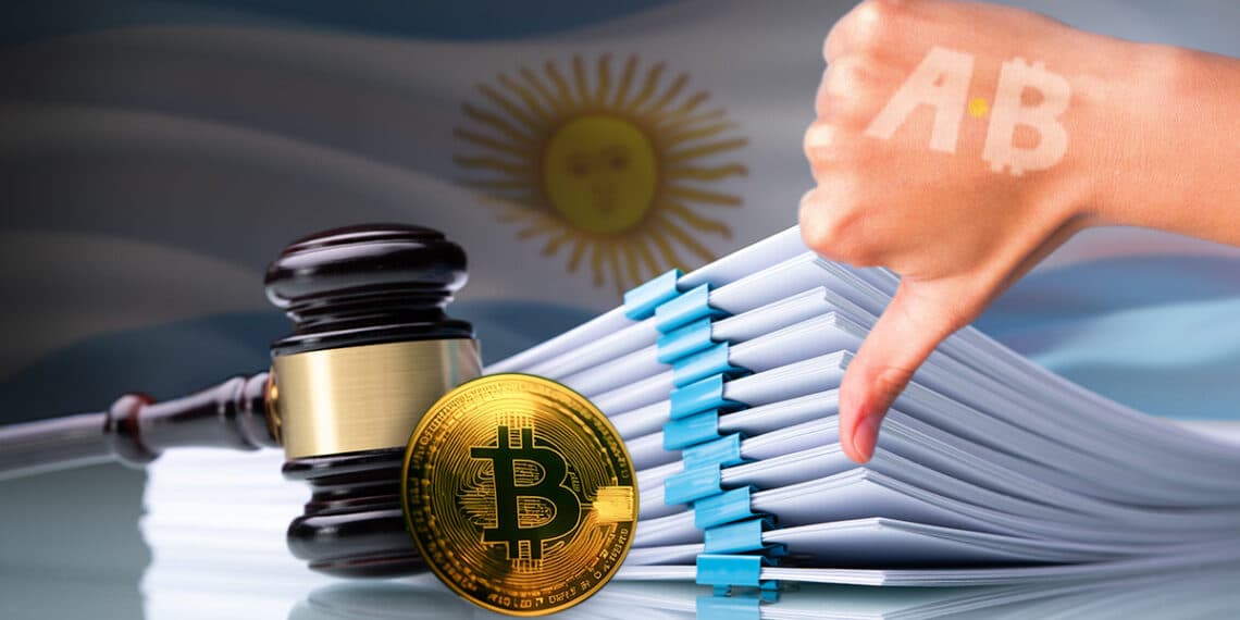 mano mostrando señal de disgusto con logo de Bitcoin Argnetina hacia moneda de bitcoin apoyada en martillo de juez junto a documentos legales con bandera de Argentina en el fondo