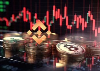 monedas de bitcoin y bnb sobre mesa con grafico de precio bajista en el fondo