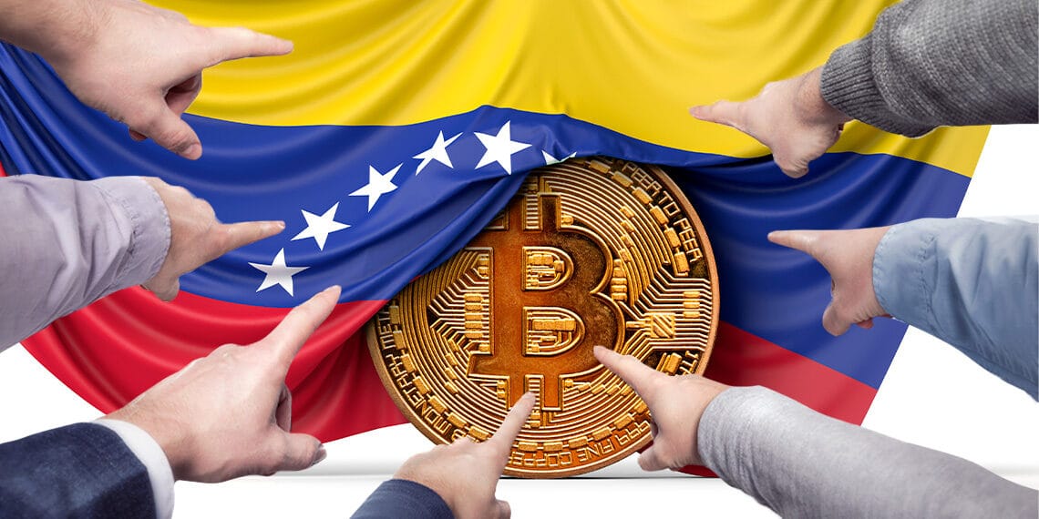 manos señalando moneda de bitcoin con bandera de venezuela