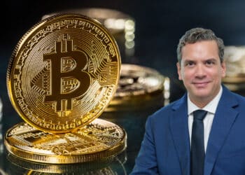 Hugo Ferrer con moneda de bitcoin en el fondo entre monedas sobre mesa