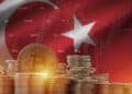 moneda de bitcoin entre pilas de monedas con bandera de Turquia con grafico de precio en el fondo