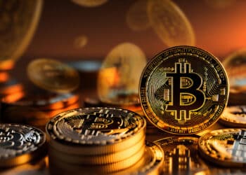 monedas de bitcoin apiladas sobre mesa de cristal con monedas de bitcoin cayendo en el fondo