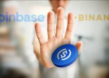 moneda de usdc siendo deteinad por mano con logos de Binance y coinbase en el fondo