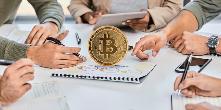 moneda de bitcoin sobre documento entre personas