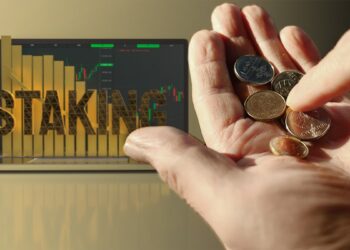 persona contando monedas sobre la palma de su mano con computadora haciendo staking de criptomonedas en el fondo