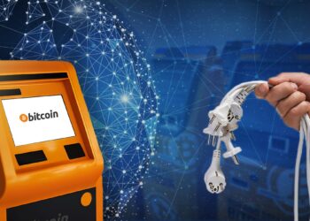 mano sostiene cables de poder desconectados junto a cajero de bitcoin con mundo digital y cajeros de bitcoin en el fondo