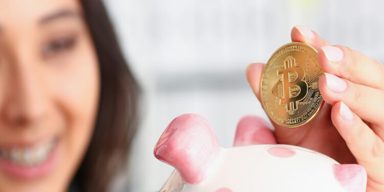 mujer depositando moneda de bitcoin en alcancía