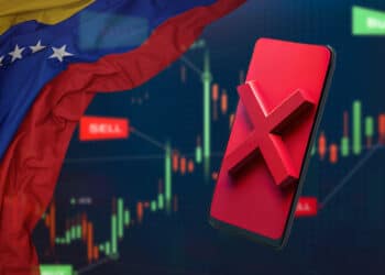 Bandera de Venezuela junto a celular con cruz roja y exchange de fondo.