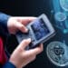 persona sosteniendo gameboy con bitcoins en pantalla con bitcoins en red en el fondo