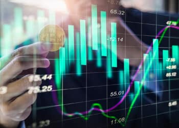 hombre sosteniendo moneda de bitcoin con grafico de velas verdes superpuesto