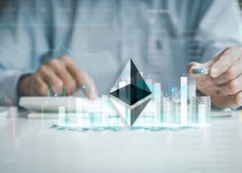 logo de ethereum sobre mesa con monedas apiladas con grafico de precio