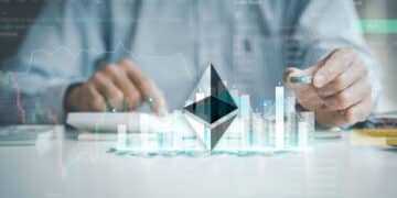 logo de ethereum sobre mesa con monedas apiladas con grafico de precio