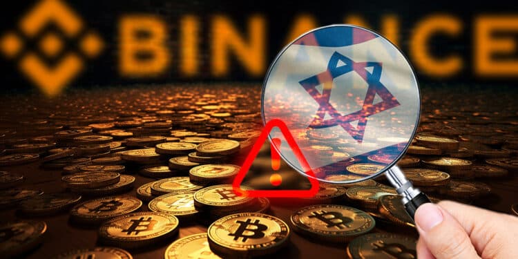mano sosteniendo lupa con bandera de Israel sobre monedas de bitcoin esparcidas sobre habitacion oscura con logo de binance en el fondo mostrando señal de alerta