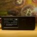 Jade Wallet sobre mesa con reloj de arena y monedas de bitcoin siendo minadas en el fondo