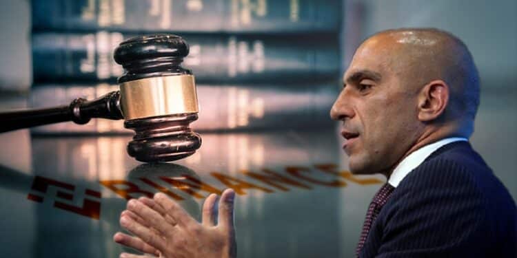 El jefe de la CFTC, Rostin Behnam con escritorio legal con logo de Binance reflejado