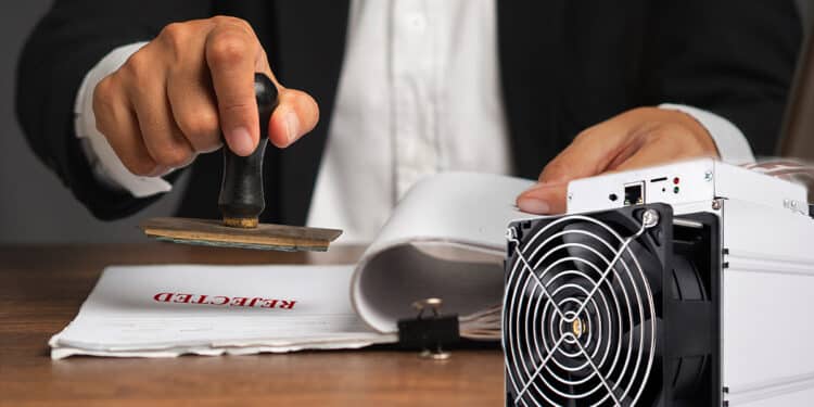 minero asic de bitcoin con persona sellando documentos con sello de rechazo