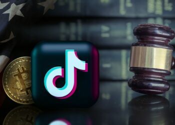 toho de tiktok con moneda de bitcoin detras y bandera de Estados Unidos superpuesta junto a martillo de juez con libros de leyes en el fondo