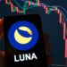 logo de Luna en telefono movil con grafico de precio bajista en el fondo