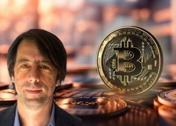 maximiliano Carjuza, con moneda de bitcoin entre monedas en el fondo