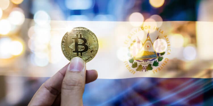 mano sostiene moneda de bitcoin con bandera de El Salvador en el fondo