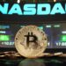 moneda de bitcoin con pantallas de NASDAQ en el fondo