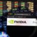 lupa enfocando página web de nvidia con graficos de mercado de valores en el fondo