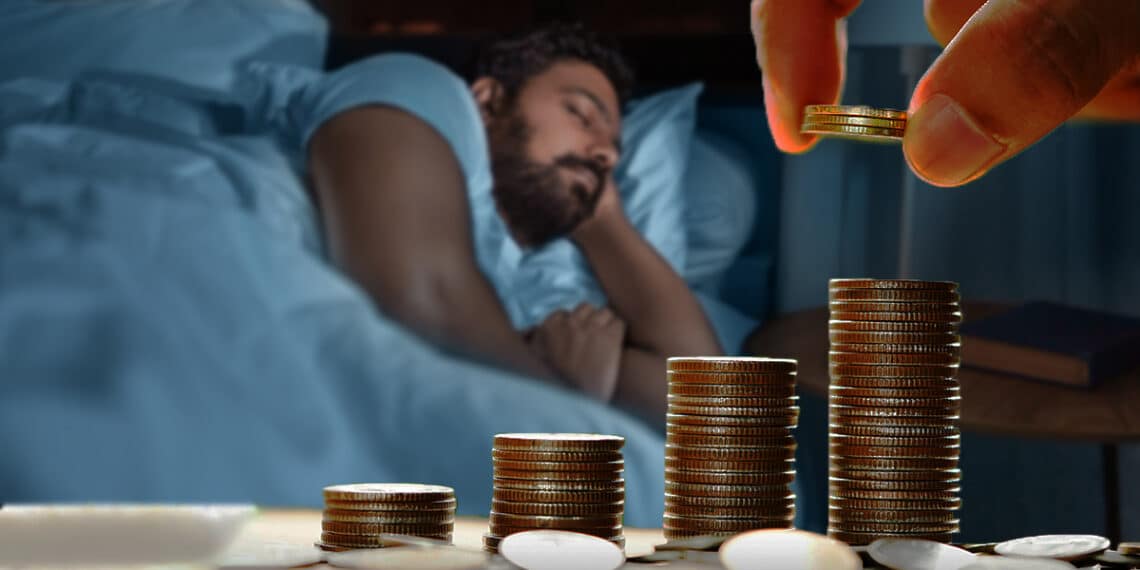 mano apilando monedas con persona durmiendo en el fondo