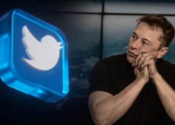 logo de twitter en placa de cristal azul junto a elon musk