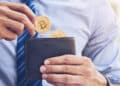 persona colocando monedas de bitcoin en billetera