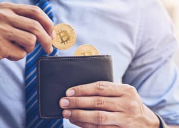 persona colocando monedas de bitcoin en billetera